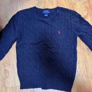 Mörkblå Kabelstickad Polo RL tröja - Snygg mörkblå stickad tröja från Polo Ralph Lauren. Tröjan är bra att ha under jackan och varm, perfekt för kyligare dagar. Kontakta oss vid frågor! Pris är diskuterbart😁