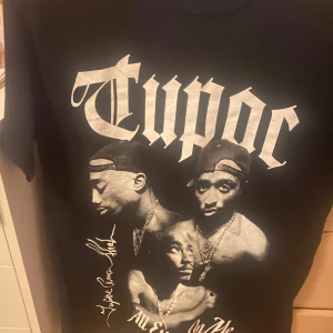 2Pac T-shirt  - Cool svart T-shirt med stort tryck av Tupac. Säljer till brorsa. Använd mycket men fortfarande väldigt bra skikt och väldigt cool 