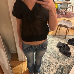 Svart transparent blus - Snygg svart blus med korta ärmar och knappar framtill. Den är lite genomskinlig, perfekt för fest. Lappen borta, men från vero Moda!