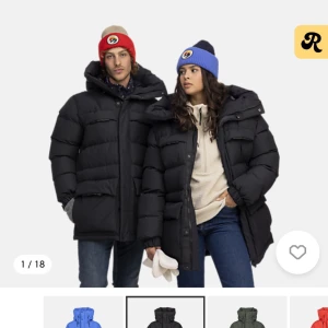 Svart dunjacka  - Snygg och varm svart dunjacka med en stor huva och logotyp på ärmen. Jackan har långa ärmar och flera praktiska fickorl. Perfekt för kalla dagar. Använd 2ggr så som ny! Nypris 1999kr