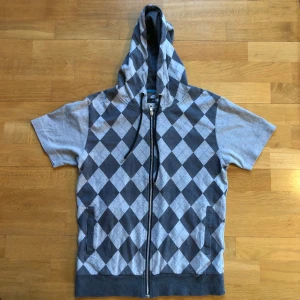 Grå hoodie med diamantmönster - Snygg grå hoodie med korta ärmar och dragkedja. Den har ett stilrent diamantmönster i mörkgrått och ljusgrått på framsidan och huvan. Perfekt för en avslappnad stil. Köpt i japan