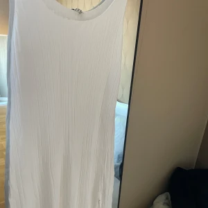Vit ärmlös klänning - Säljer en stilren vit ärmlös klänning med ribbad struktur. Perfekt för varma dagar med sin enkla och eleganta design.