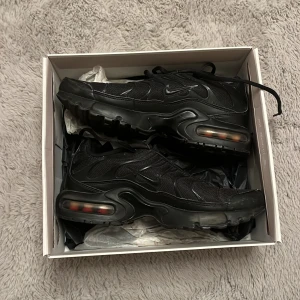 Svarta Nike sneakers - Säljer ett par svarta Nike sneakers med synlig luftdämpning i sulan. Skorna har en sportig design med snörning och är tillverkade i syntetmaterial. Ganska använda men ser fräcsha ut.