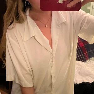 Vit kortärmad skjorta - Snygg och stilren vit skjorta med korta ärmar och klassisk krage. Perfekt för en avslappnad men ändå uppklädd look. Skjortan har knappar framtill och en lös passform som ger en bekväm känsla.