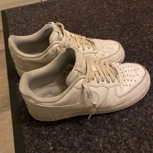 Vita Nike Air Force one sneakers - Säljer ett par klassiska vita Nike Air Force sneakers. Skorna har en stilren design med snörning och perforerade detaljer på ovansidan för ventilation. Perfekta för en avslappnad och sportig look.