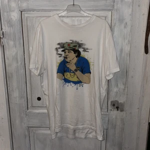 Maradona t-shirt  - Säljer en vit t-shirt från Nakata med ett tryck på Maradona. Nypris 369 kr. 