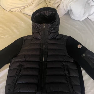 Svart pufferjacka från Moncler - Snygg svart pufferjacka från Moncler med quiltad design och dragkedja. Jackan har långa ärmar och en hög krage för extra värme. Perfekt för kyliga dagar! Använd bara några få gånger.