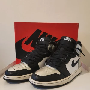 Nike Air Jordan 1 High OG - Snygga Nike Air Jordan 1 High OG silver toe i svart, vit och metallic silver. Skorna har klassisk snörning och en ikonisk design med Nike-logga på sidan. Perfekta för sneaker-entusiaster som vill ha en stilren look. Skolan kommer med original förpackning och extra skosnören.