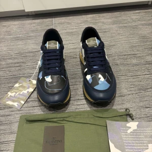 Valentino Rockrunner sneakers - Snygga Valentino Rockrunner sneakers med ett coolt kamouflagemönster i blått, svart och vitt. Skorna är väldigt eftertraktade, vad som ingår: Dustbag, och box till skorna samt skorna såklart.  Skicket på skorna är 10/10 då dem är helt nya och oanvända. Pris kan diskuteras vid snabb affär 