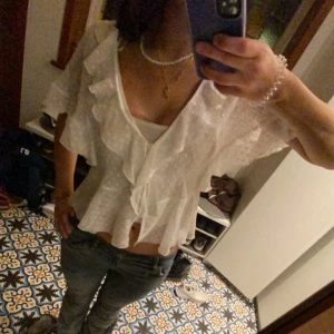 Vit blus med volanger - Såå söt vit blus med volanger från Zara. Blusen har korta ärmar och en luftig passform, perfekt för fest. Använd max 3 ggr så är i nästan helt nytt skick💗💗