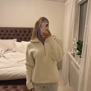 Vit ribbad tröja med dragkedja - Säljer en stilren vit ribbad tröja med dragkedja och hög krage. Perfekt för kyligare dagar med sin mysiga och bekväma passform. Tröjan har långa ärmar och är gjord i ett mjukt material.