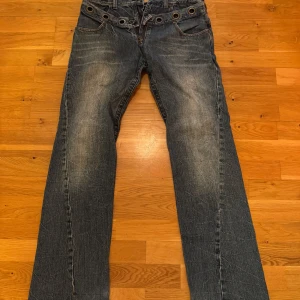 Blå jeans med slitna detaljer - Riktigt feta par blå jeans med coola slitna detaljer thrifted i Vietnam! Jeansen har en straight passform och är vida där nere. De har flera knappar i midjan. Storlek S/M men relativt långa. Jag är 171 cm.