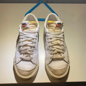 Vita Nike blazer - Säljer ett par klassiska vita Nike sneakers med svart swoosh. Skorna har snörning och en retro design som passar perfekt till vardagsstilen. De har en bekväm passform och är ett måste för sneakerälskare. Pris kan diskuteras (og medföljer)