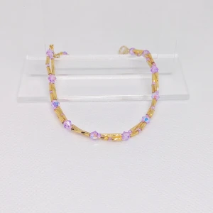 Lila armband med gulddetaljer  - Säljer ett lila armband med guldfärgade stavar. Perfekt för att lägga till en färgklick till din outfit. Armbanden har en fin kedja och är lätta att matcha med andra smycken. OBS! Denna annons gäller endast det lila armbandet.