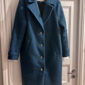 Blå kappa från Kaffe - Snygg blå kappa från Kaffe med knappar framtill och långa ärmar. Perfekt för kyligare dagar med sin mysiga och stilrena design.