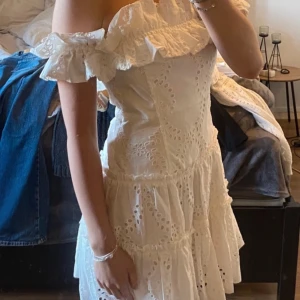 Vit offshoulder klänning med volang / studentklänning  - Charmig vit klänning med offshoulder-design och volangdetaljer. Klänningen har ett vackert broderat mönster och är perfekt för sommarens festligheter. Dragkedja finns på ena sidan!🧸🌸