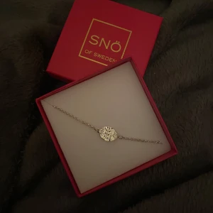 Silverarmband från SNÖ of Sweden - Elegant silverarmband från SNÖ of Sweden med ett vackert, cirkulärt hänge. Perfekt för att lägga till en touch av stil till din outfit. Kommer i en snygg röd presentask.