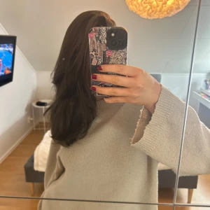 Beige stickad tröja - Mysig beige stickad tröja med långärmad design. Perfekt för kyligare dagar med sin mjuka och bekväma passform. Enkel och stilren, passar till många olika outfits. Den är något nopprig som även syns på bilden. 