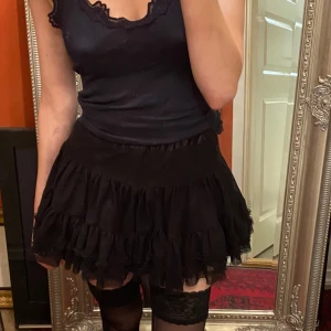 Svart miniskirt - Trendig svart kortkjol med volanger. Perfekt för att skapa en chic look. Kjolen har en elastisk midja för bekväm passform. Säljer då den inte längre passar min stil💕 passar s-xs