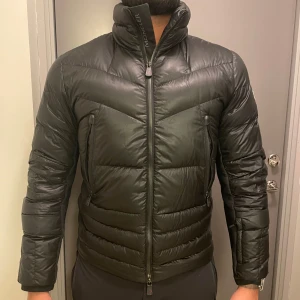 Moncler Grenoble - Snygg svart dunjacka från Moncler med quiltad design och dragkedja. Jackan har en hög krage och Moncler-logga på ärmen. CANMORE SHORT DOWN JACKET