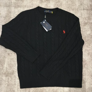 Svart Stickad Polo Ralph Lauren Tröja - Säljer en stilren svart stickad tröja från Polo Ralph Lauren. Tröjan är perfekt inför vintern då den värmer hur bra som helst. Fräsch look. Säljs då jag inte diggar den stilen. Storlek S. Kan gå ned i pris vid snabb affär