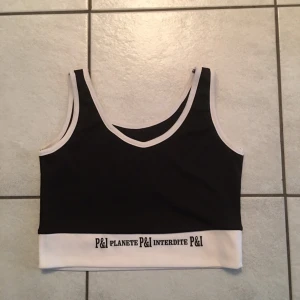 Svart och vit linnetopp från Planete Interdite - Snygg svart och vit linnetopp från Planete Interdite med textdetalj på nederkanten. Perfekt för en stilren look.