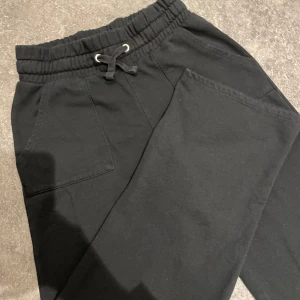 Svarta mjukisbyxor med snörning - Säljer ett par svarta mjukisbyxor från lager 157 i storlek S. Byxorna har en elastisk midja med snörning och praktiska fickor både fram och bak. Perfekta för en avslappnad stil!💕 Har två par av dessa som jag säljer, båda väldigt lita använda 