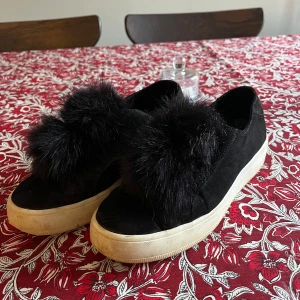 Svarta sneakers med pälsdetalj från Steve Madden - Snygga svarta sneakers från Steve Madden med en unik pälsdetalj på ovansidan. Skorna har en vit sula som ger en cool kontrast till det svarta. Perfekta för att ge din outfit en trendig touch.