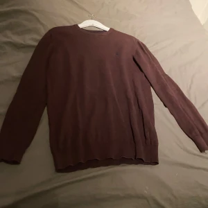 Vinröd tröja  - Säljer vinröd tröja. Tröjan har långa ärmar och en rund halsringning med ribbade detaljer vid ärmslut och nederkant. Perfekt för kyligare dagar.