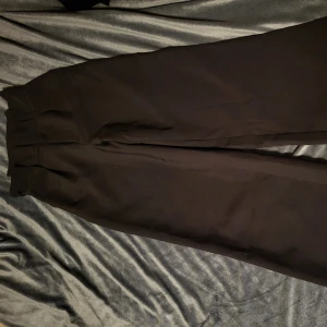 Svarta kostymbyxor från Bik Bok - Snygga svarta kostymbyxor från Bik Bok i storlek XS. Byxorna har en klassisk design med rak passform och hög midja, perfekta för en stilren look. Tillverkade i ett bekvämt material som ger en elegant känsla.