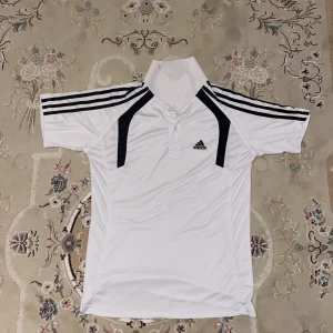 Vit sporttröja från Adidas - Vit sporttröja från Adidas. Perfekt för en sportig look. Adidas-loggan är broderad på bröstet.