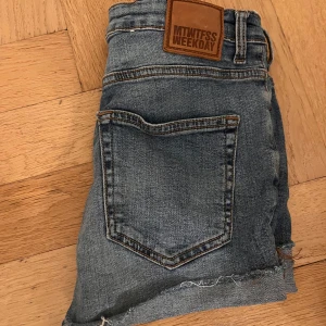 Jeansshorts från Weekday - Snygga jeansshorts från Weekday i klassisk blå denim. De har en högmidjad passform och slitna detaljer vid fållen för en trendig look. Perfekta för sommardagar!