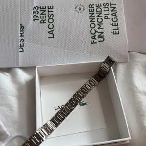 Armband Lacoste - Aldrig använt, kvitto finns. Köpt i Frankrike. Presentask och påsen medföljer!