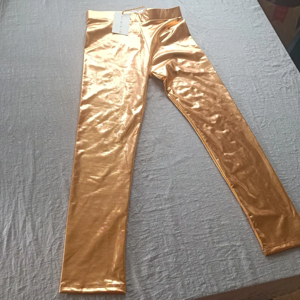 Säljer ett par supercoola guldglänsande leggings från Minimarket för barn 6- 8 år. De är i en skinande guldfärg och har en tight passform som verkligen sticker ut. Perfekta för en fest eller när du bara vill känna dig extra glamorös!. Jeans & Byxor.