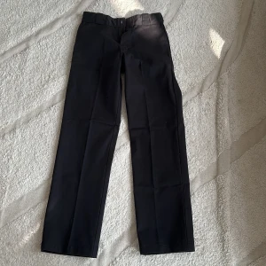 Svarta byxor från Dickies - Säljer ett par klassiska svarta Dickies 874 Original Fit byxor. De har en rak passform och är perfekta för både vardag och arbete. Byxorna är i bra skick och har en stilren design med hällor för bälte.