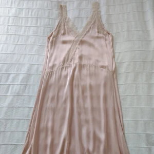 Slip dress med spets - dusty pink - storlek 34 (XS-M) - En glansig slip dress i något silkesliknande material med spetskant. Bara använd ett par gånger och i fint skick (en del "dragna trådar" i spetsen). Storlek 34 men jag skulle säga att den även passar större storlekar.