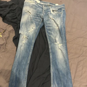 Blåa dondup jeans med slitningar - Ett par feta dondups med slitningar i stlrk 34, sitter som slim fit jeans Priset är inte helt fast