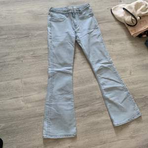 Säljer ett par ljusblå jeans från H&M med utsvängda ben. De har låg midja och justerbar midja för perfekt passform. Perfekta för en avslappnad och trendig look!