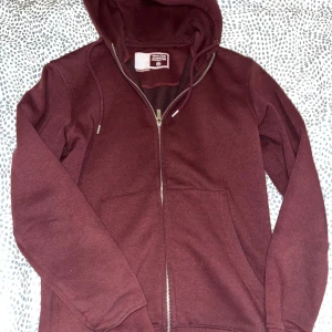 Vinröd hoodie från Solid - Säljer en vinröd hoodie från Solid i storlek XS. Den är supermysig och perfekt för höst och vinter. Hoodien har en dragkedja framtill . Den är i bra skick och väldigt bekväm att ha på sig. Perfekt för både vardag och chillkvällar!