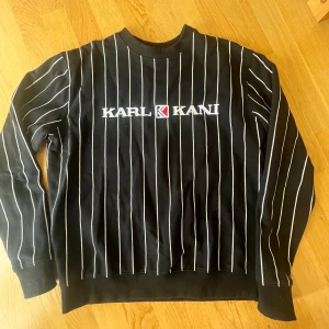 Svart randig tröja från Karl Kani - Säljer en snygg svart tröja från Karl Kani med vita ränder. Den har en klassisk passform och är perfekt för både vardag och chill. Tröjan är i storlek S och är i bra skick. Perfekt för höst och vinter! använd fåtal gånger