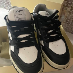 Svartvita sneakers från Axel Arigato - Snygga svartvita sneakers från Axel Arigato med stilren design. Skorna har en robust sula och klassisk snörning. Perfekta för en trendig look.