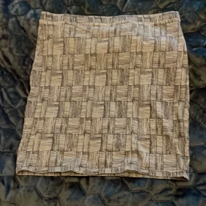 Kort kjol från Monki - Säljer en kort mönstrad kjol från Monki i storlek medium. Kjolen har ett unikt rutigt mönster i beige och grå toner. Tillverkad av bomull med en liten del elastisk så den är mjuk och stretchig. 