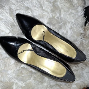 Svarta festskor spetstå med klack blanka - Eleganta svarta pumps i lack med spetsig tå och hög klack. Perfekta för en stilren look. 