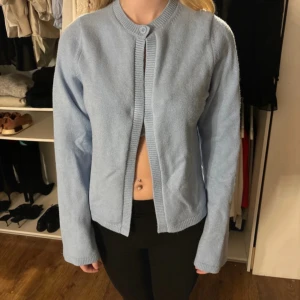 Ljusblå kofta - Säljer en ljusblå kofta med rund halsringning och långa ärmar. Koftan har en enkel design med ribbade kanter och är perfekt för en avslappnad stil. Från Gina tricot storlek S