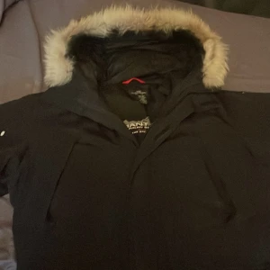 Svart vinterjacka från Gant - Säljer en svart vinterjacka från Gant med pälsfodrad huva. Jackan har dragkedja och flera fickor. Perfekt för kalla dagar riktigt varm och skön Stor i storleken. Tre små håll som jag tog med på bilden lätt att sy därför lägger jag ut den för mycket lågt pris 🏆 