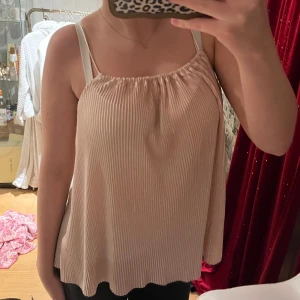 Rosa  ärmlös topp - Säljer en stilren rosa ärmlös topp med smala axelband. Toppen har en luftig passform och ett diskret randigt mönster. Perfekt för varma dagar!