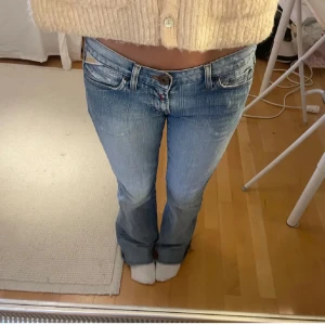 ljusblåa jeans från Replay - Snygga blå jeans från Replay(strlk 25x32)med broderade detaljer och en unik rosa etikett med blommönster. De har en bootcut-stil och låg midja (37cm rakt över vid midjan). Köpta på Plick men är för stora på mig så säljer vidare. Skriv vid funderingar 😊💕