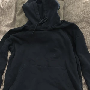 Mörkblå hoodie från Jack & Jones - Säljer en stilren mörkblå hoodie från Jack & Jones. Den har en klassisk design med en stor ficka framtill och justerbar huva med dragsko. Perfekt för en avslappnad look.