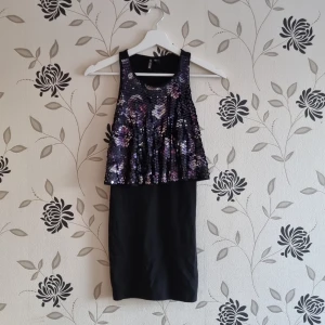 Svart paljettklänning från H&M, Strl: 36,  - Snygg svart klänning från H&M Conscious Collection med glittriga paljetter i olika färger på överdelen. Klänningen har en ärmlös design och en figurnära passform som ger en elegant look. Perfekt för festliga tillfällen!