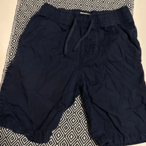 Mörkblå shorts med snörning - Säljer ett par mörkblå shorts med elastisk midja och snörning. Perfekta för en avslappnad stil under varma dagar.